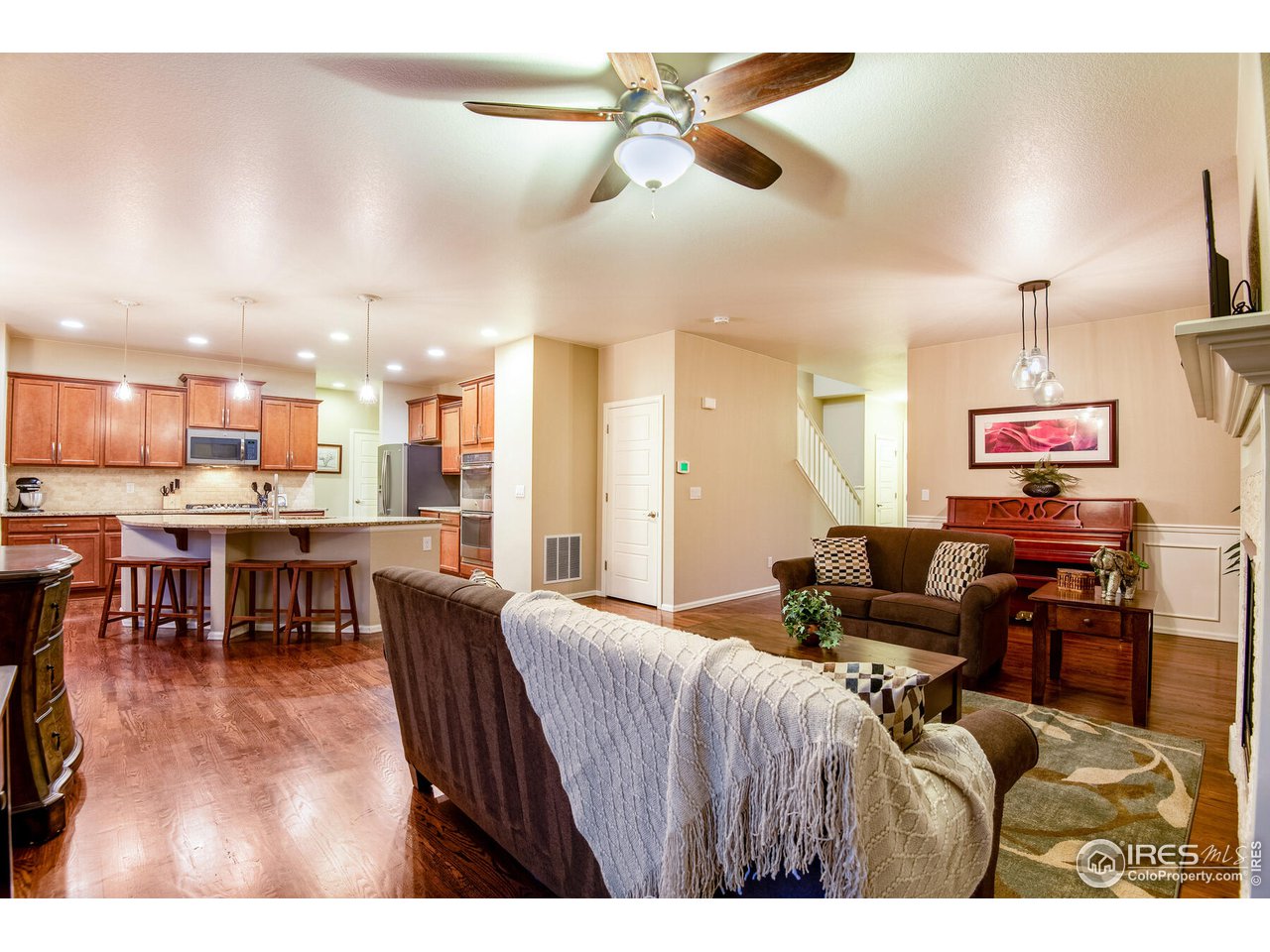 5762 Graphite Street Timnath, CO 80547 - Photo 27 of 27 a living room with furniture a ceiling fan and a kitchen view