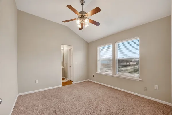 an empty room with chandelier fan and windows