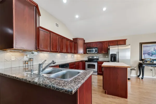 a kitchen with stainless steel appliances granite countertop a sink dishwasher and cabinets with wooden floor