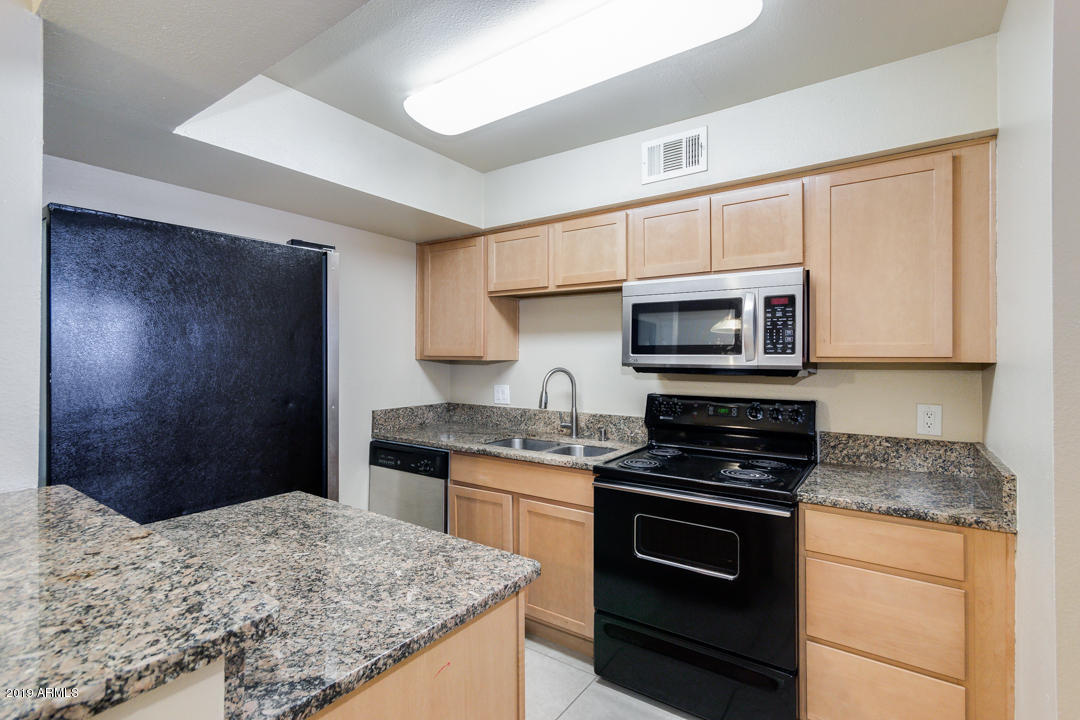 4410 North Longview Avenue, Unit 106 Phoenix, AZ 85014 - Photo 13 of 25 a kitchen with stainless steel appliances kitchen island granite countertop a stove a sink and a microwave