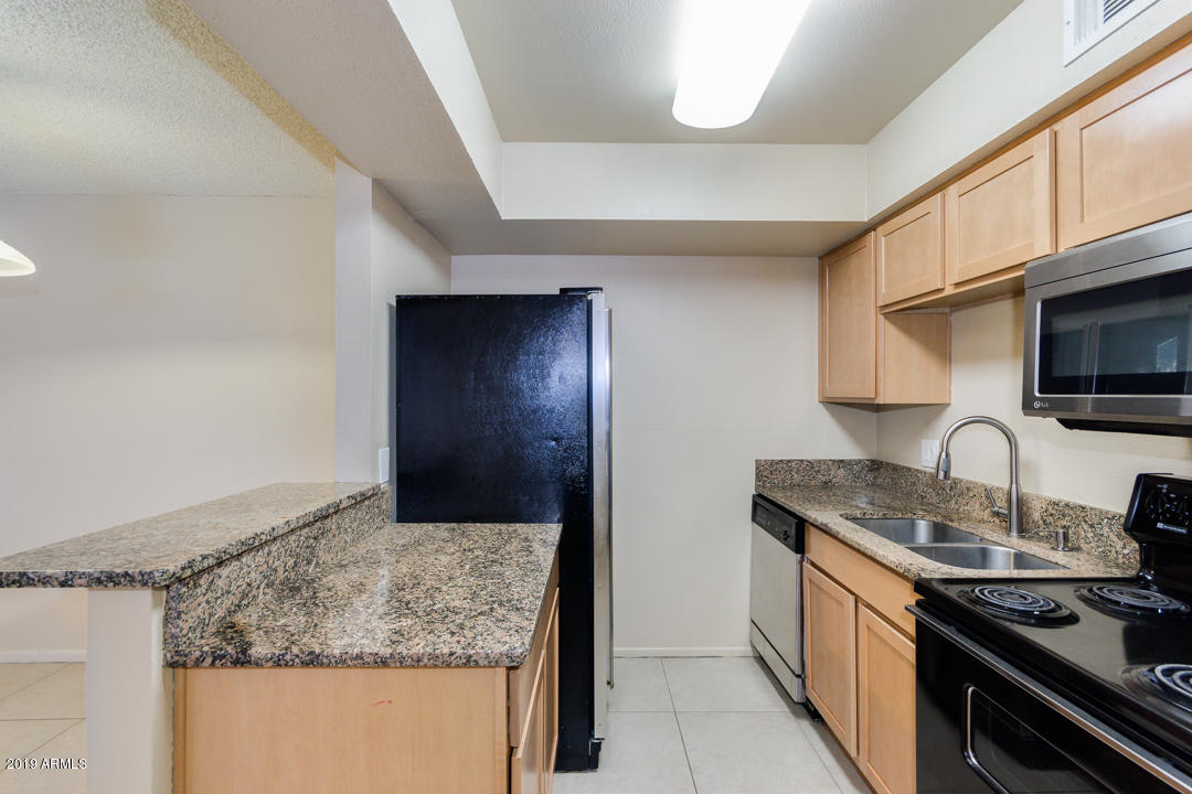 4410 North Longview Avenue, Unit 106 Phoenix, AZ 85014 - Photo 14 of 25 a kitchen with granite countertop wooden cabinets and a stove top oven