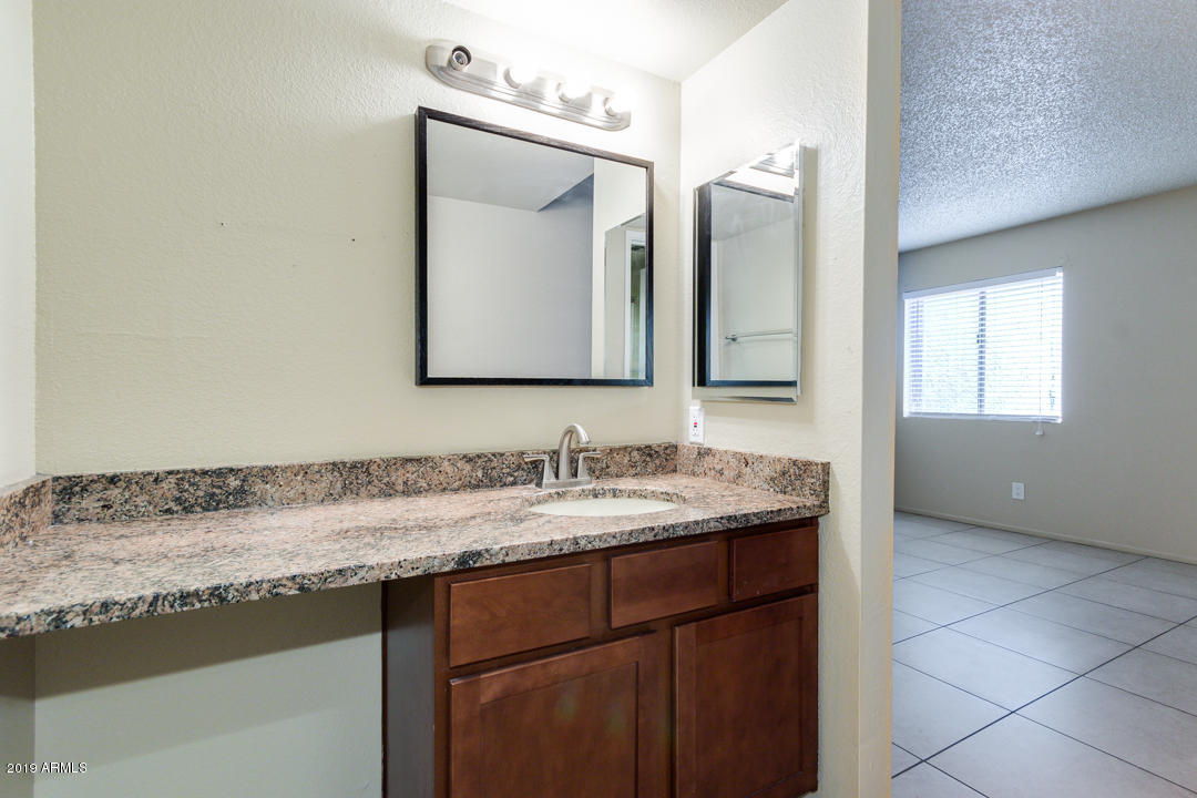 4410 North Longview Avenue, Unit 106 Phoenix, AZ 85014 - Photo 17 of 25 a bathroom with a granite countertop sink vanity and mirror
