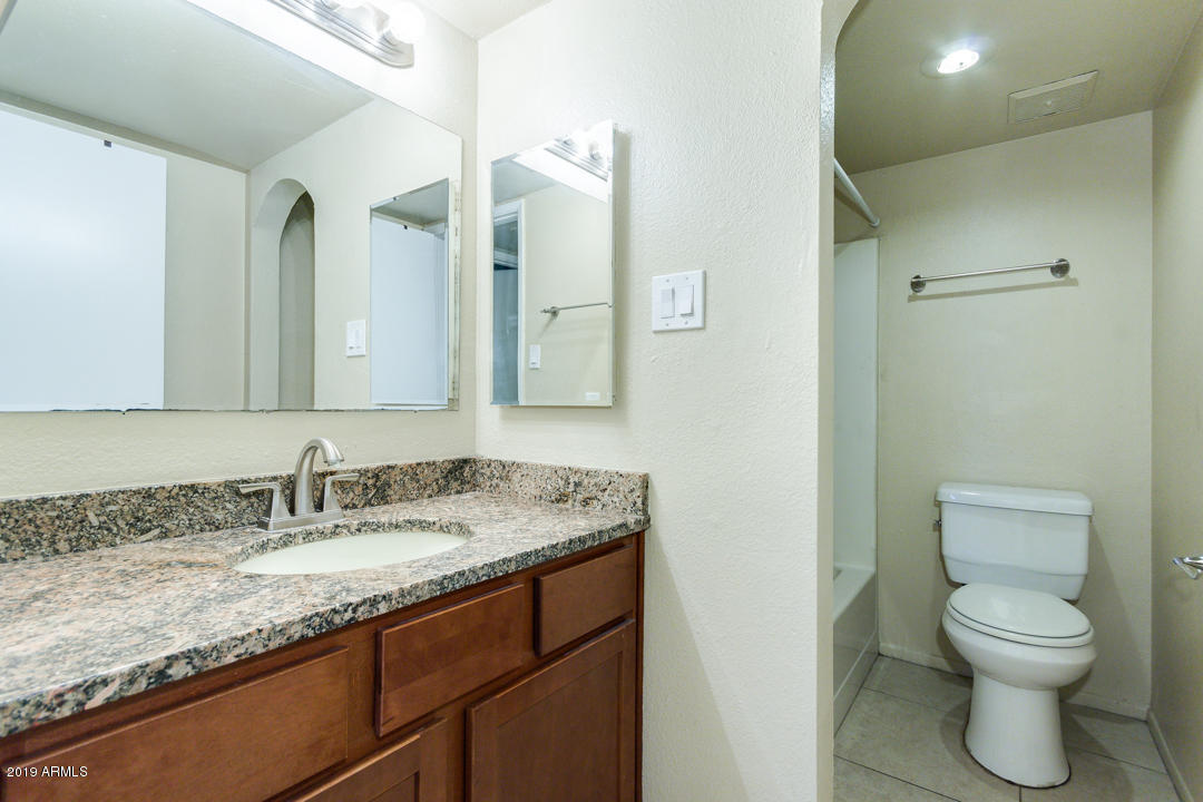 4410 North Longview Avenue, Unit 106 Phoenix, AZ 85014 - Photo 21 of 25 a bathroom with a granite countertop sink a toilet and a mirror