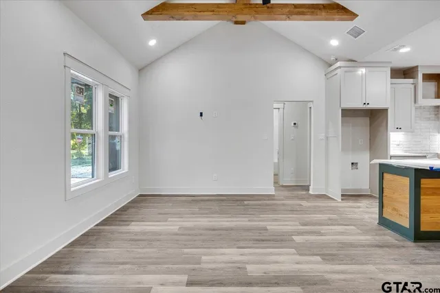 a view of an empty room with window and wooden floor