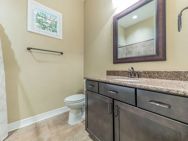 a bathroom with a granite countertop toilet sink and mirror