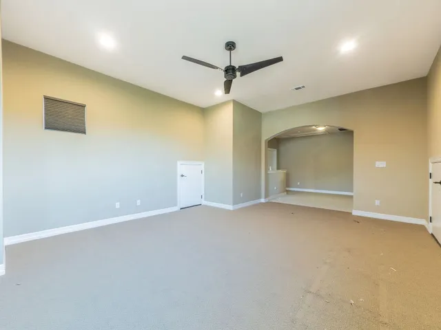 an empty room with a ceiling fan and window