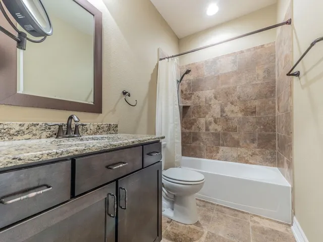 a bathroom with a granite countertop sink toilet and shower