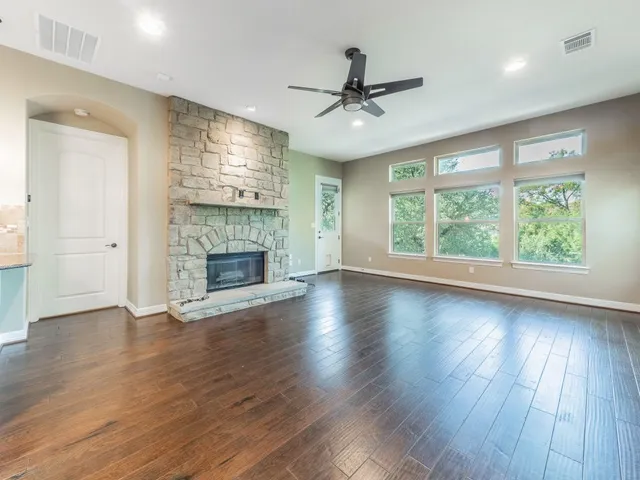 a view of an empty room with wooden floor fireplace and a window