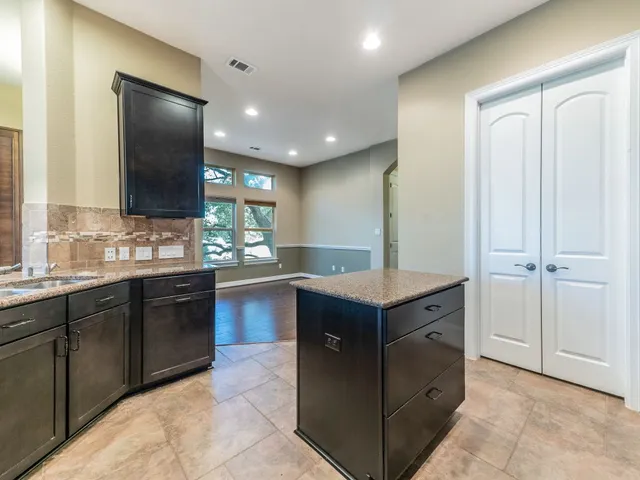 a kitchen with kitchen island granite countertop wooden cabinets and sink