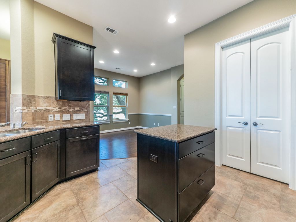 826 San Remo Boulevard Lakeway, TX 78734 - Photo 6 of 25 a kitchen with kitchen island granite countertop wooden cabinets and sink