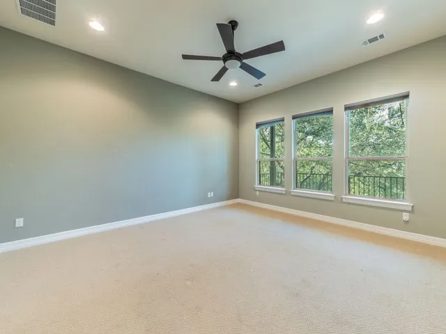 an empty room with a ceiling fan and window