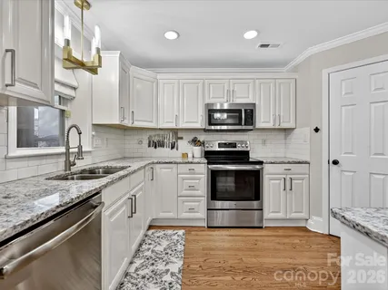 a kitchen with granite countertop a sink cabinets and stainless steel appliances