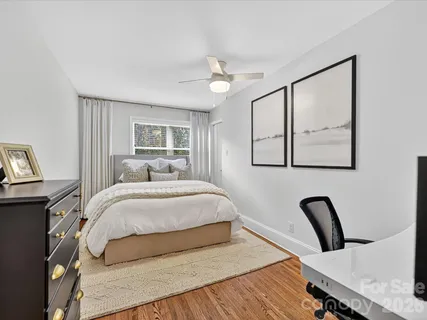 a bedroom with a bed large mirror and painting on the wall