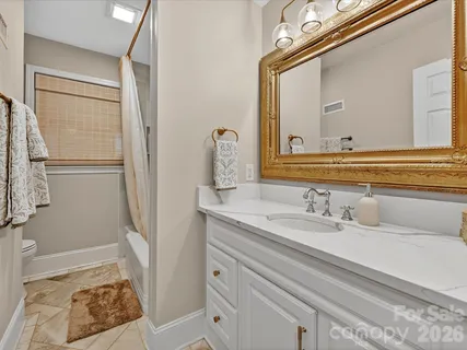 a bathroom with a granite countertop sink mirror vanity and toilet