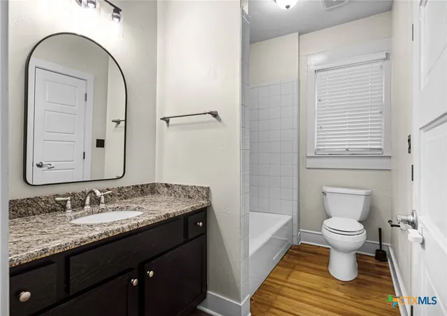 a bathroom with a granite countertop sink toilet and a mirror