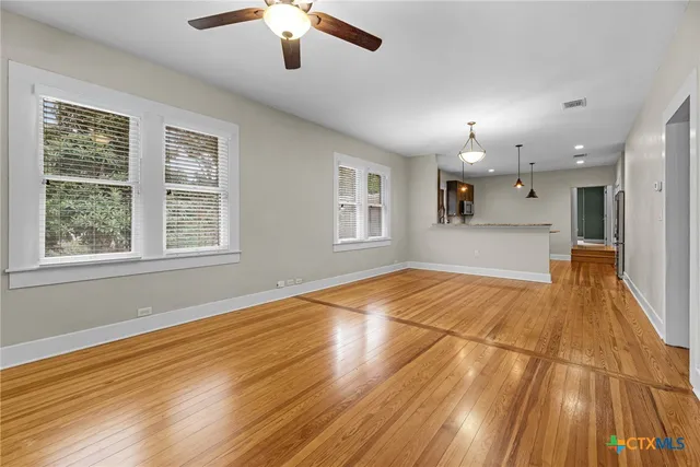 a view of empty room with wooden floor and fan
