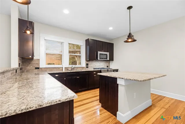 a kitchen with granite countertop a sink and a wooden floor
