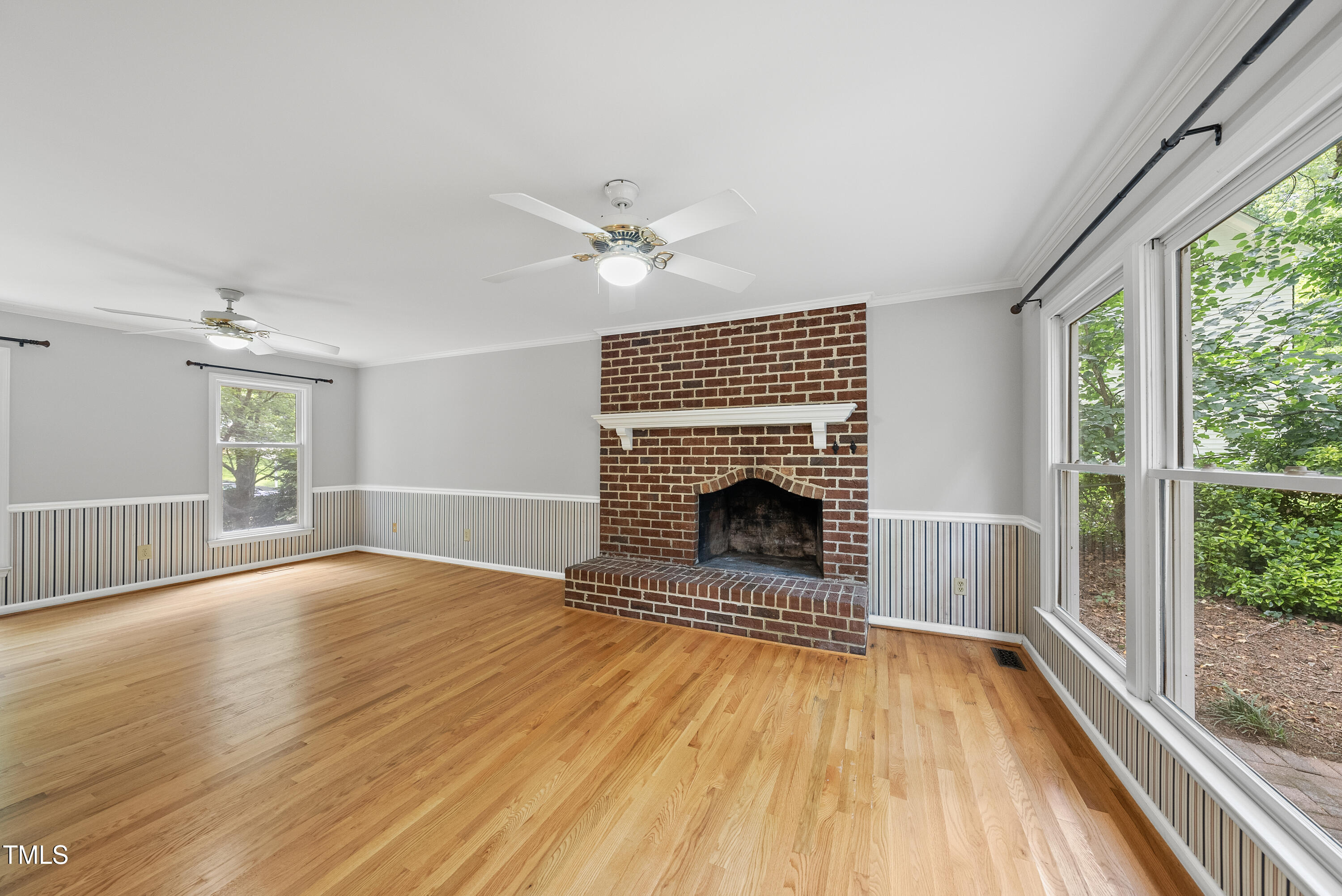 3517 Eden Croft Drive Raleigh, NC 27612 - Photo 4 of 22 an empty room with wooden floor a fireplace and windows