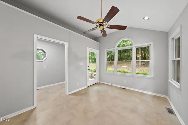 an empty room with windows and fan