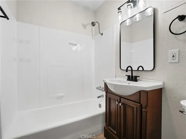 an empty room with wooden floor fireplace and windows