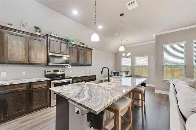 a kitchen with stainless steel appliances granite countertop a sink a stove and kitchen island