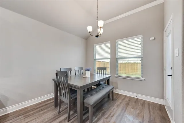 a dining room with wooden floor a chandelier a wooden table and chairs