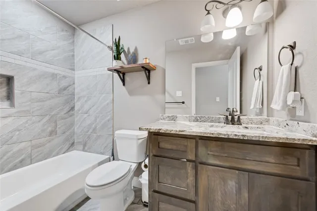 a bathroom with a granite countertop sink a toilet a mirror and bathtub