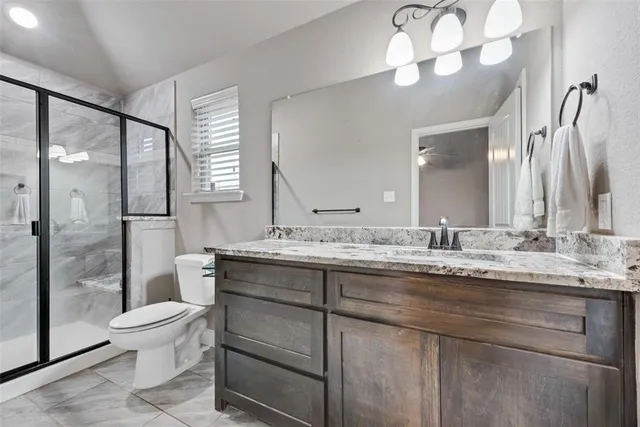 a bathroom with a granite countertop sink a toilet and a large mirror