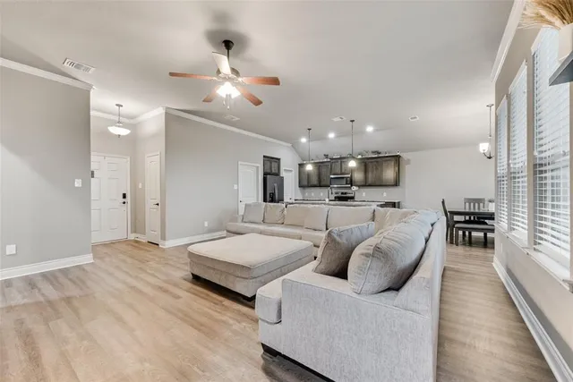 a living room with couches and kitchen view with wooden floor