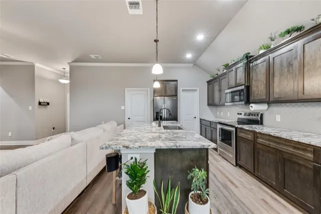 a large kitchen with kitchen island granite countertop lots of counter space a sink and appliances