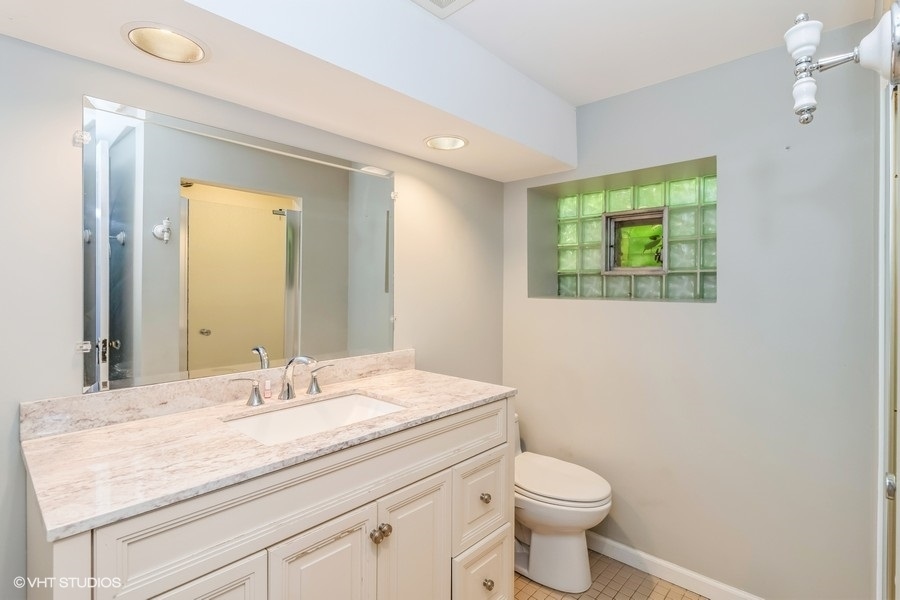 6129 North Mason Avenue Chicago, IL 60646 - Photo 18 of 22 a bathroom with a granite countertop toilet sink and mirror