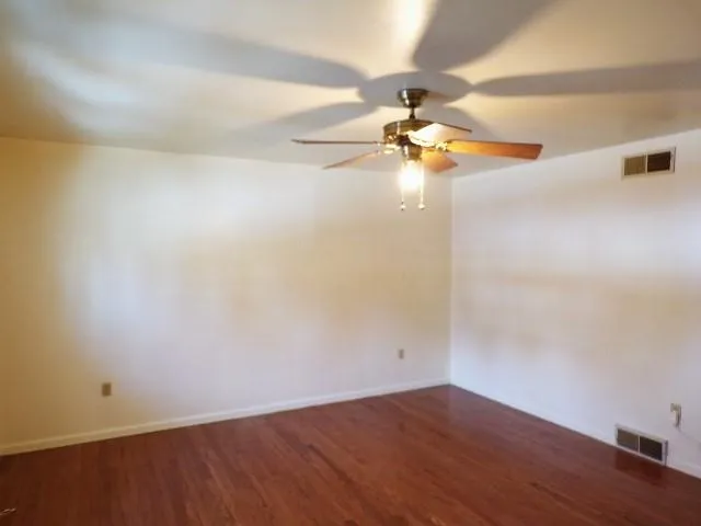 en empty room with wooden floor and fan