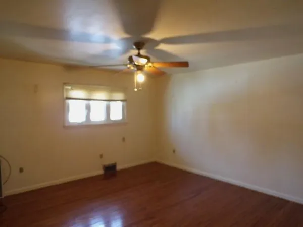 en empty room with wooden floor and fan