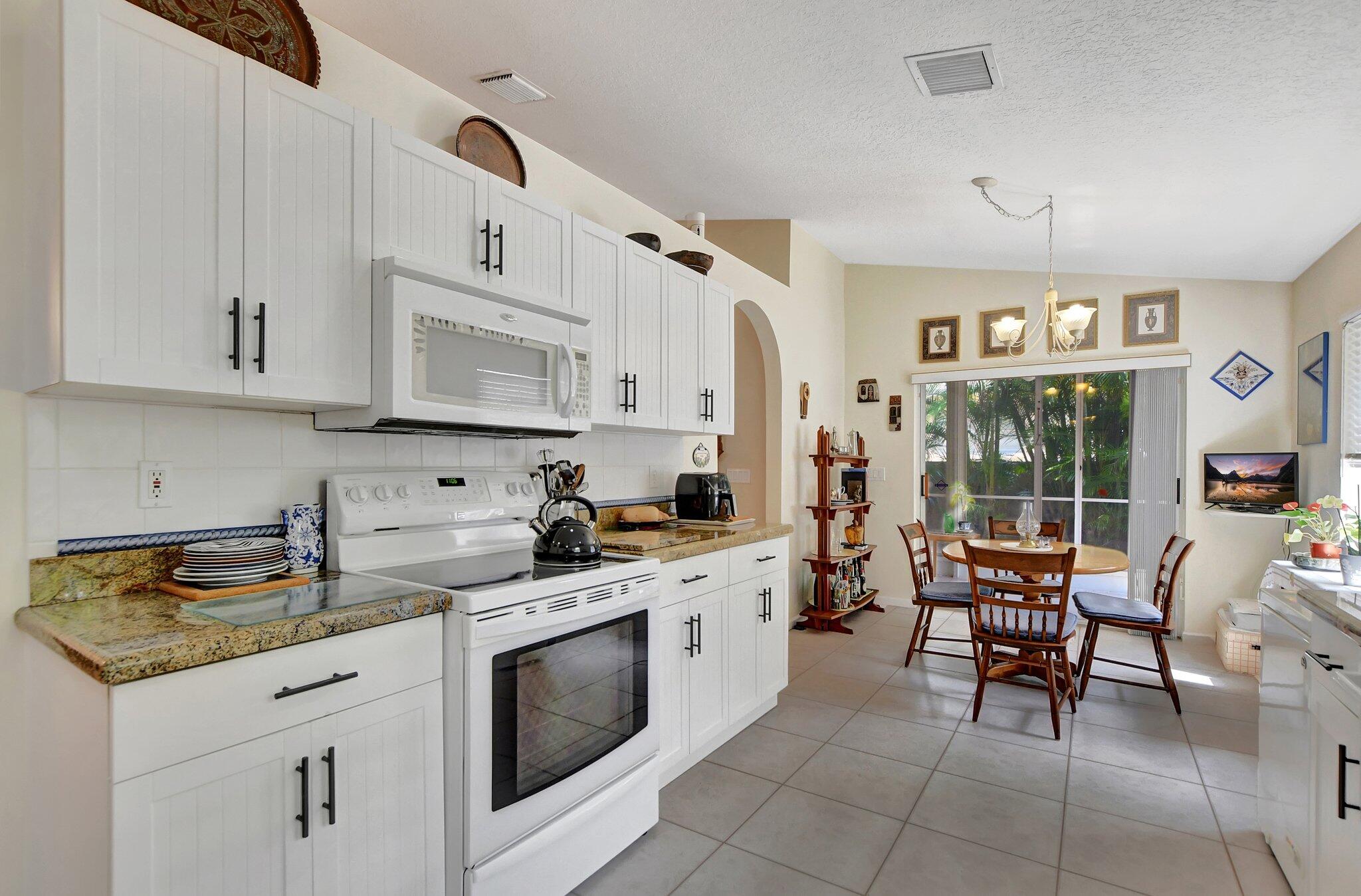 8853 Harrods Drive Boca Raton, FL 33433 - Photo 12 of 45 a kitchen with stainless steel appliances granite countertop a stove a sink and white cabinets