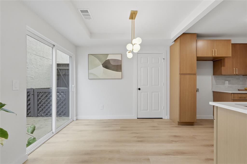 17118 Planters Row Addison, TX 75001 - Photo 6 of 18 Open-concept living area featuring wood-finish flooring, a modern chandelier, and sliding glass doors leading to an outdoor patio