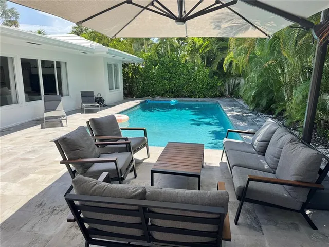 a backyard of a house with table and chairs under an umbrella