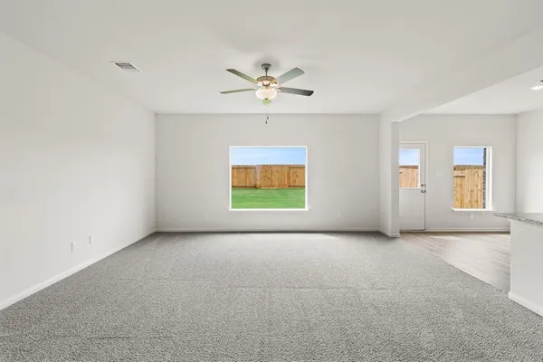 an empty room with windows and ceiling fan