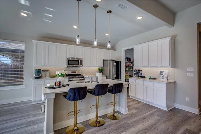 a kitchen with stainless steel appliances granite countertop a stove top oven a refrigerator a sink and chairs