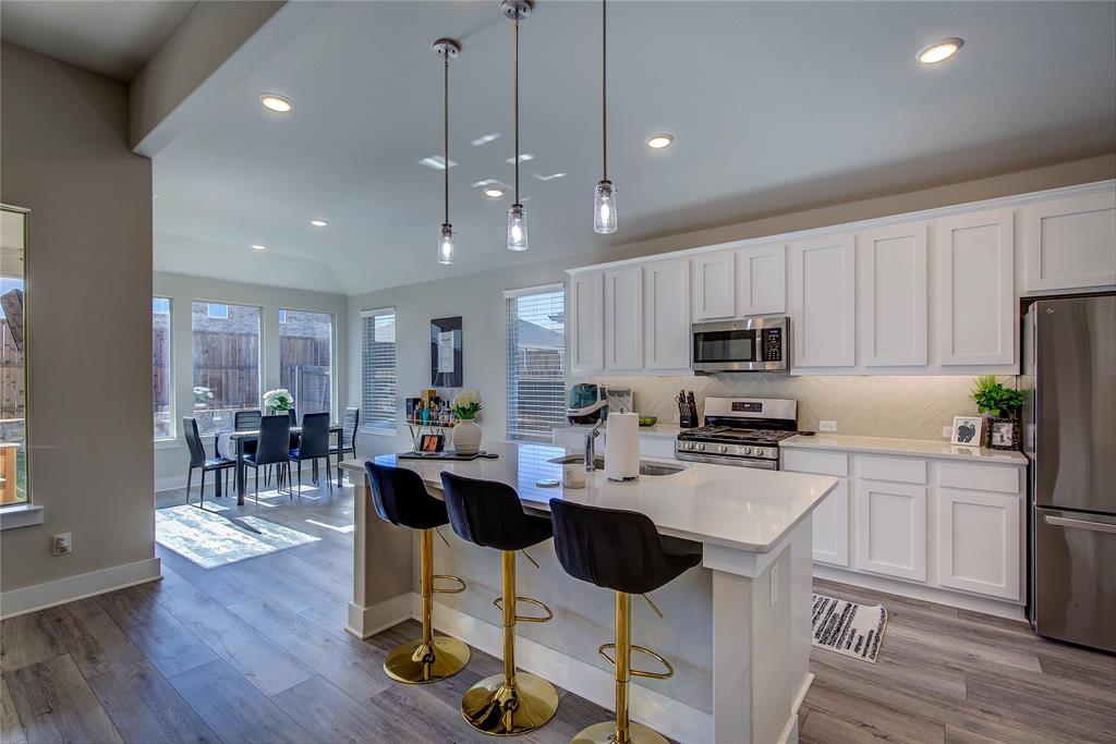 1872 Big Spring Drive Forney, TX 75126 - Photo 13 of 40 a kitchen with stainless steel appliances kitchen island granite countertop a stove a refrigerator a sink a dining table and chairs with wooden floor