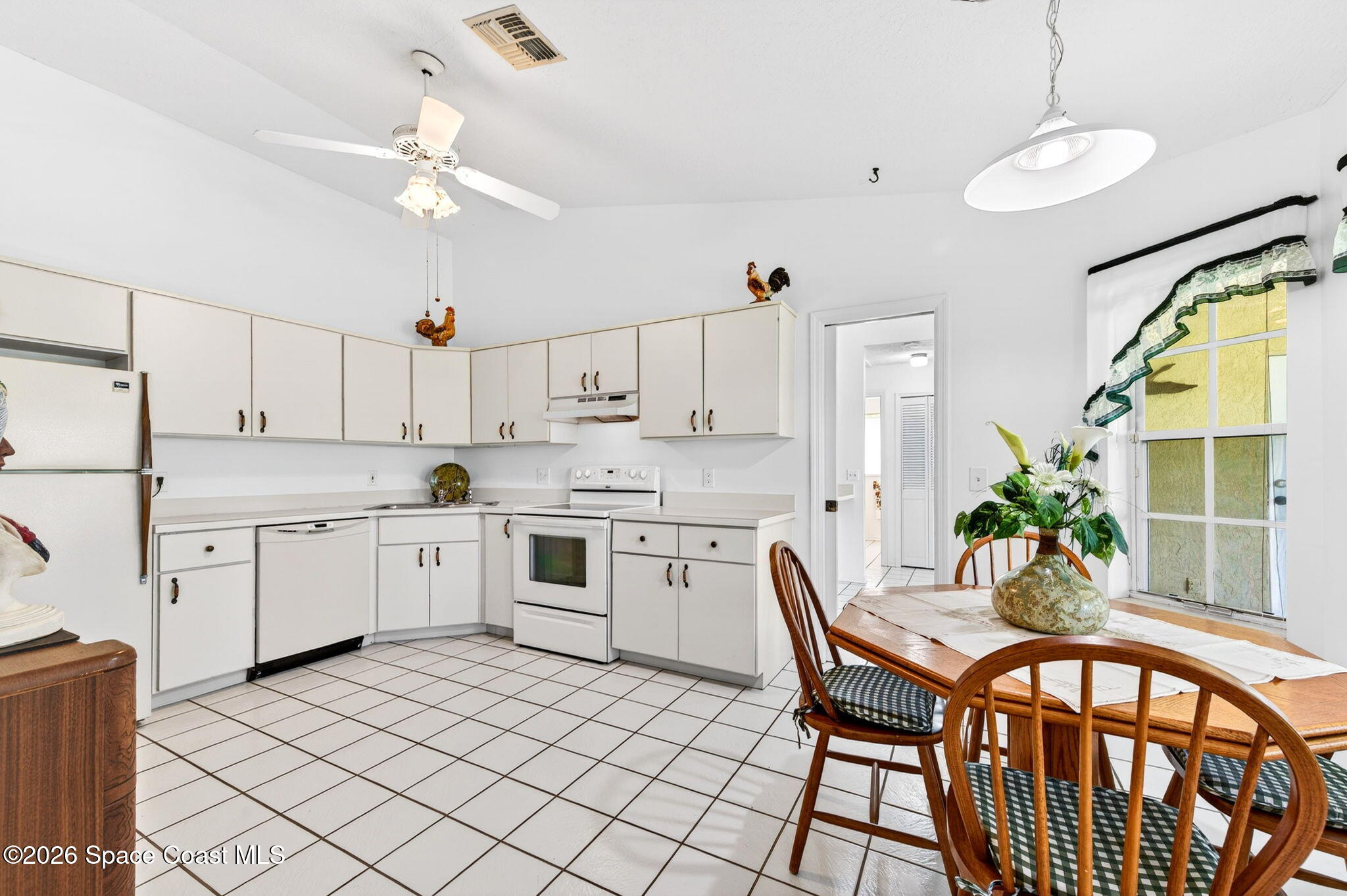 1455 Atz Road Malabar, FL 32950 - Photo 35 of 73 a kitchen with a dining table chairs and white cabinets