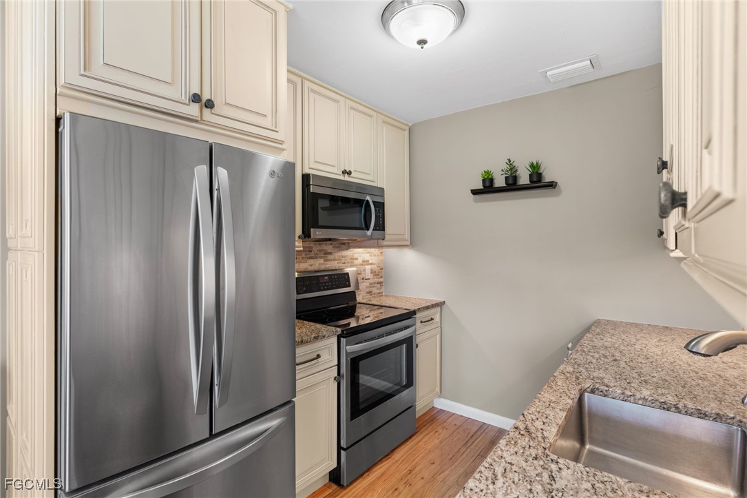 601 Periwinkle Way, Unit C5 Sanibel, FL 33957 - Photo 17 of 35 a kitchen with stainless steel appliances granite countertop a refrigerator stove and microwave