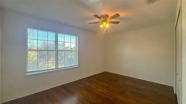 a view of an empty room with wooden floor and window