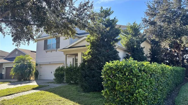 a view of a house with a small yard plants and large tree