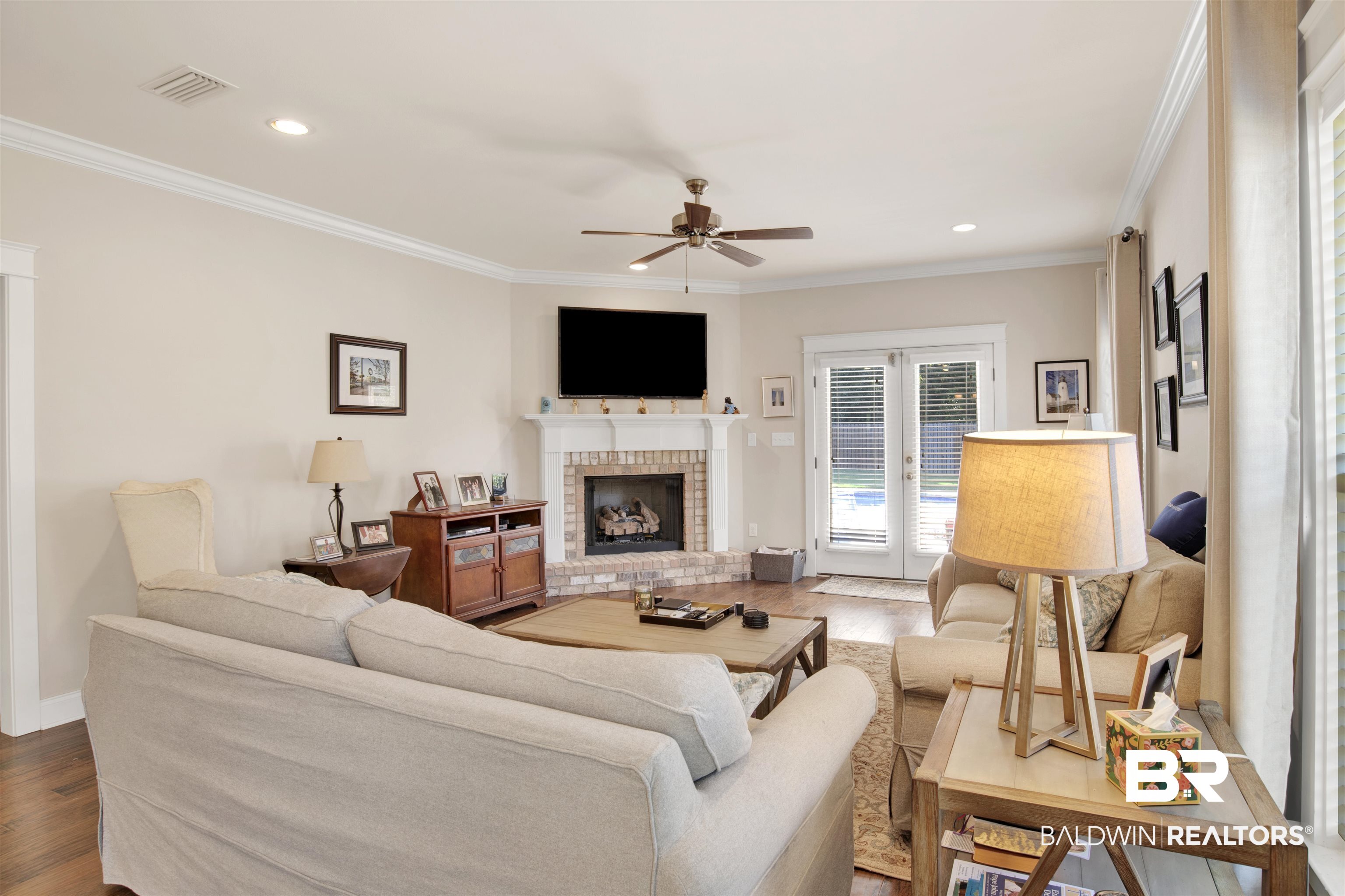 360 Scarlett Avenue Fairhope, AL 36532 - Photo 20 of 34 Living room with a brick fireplace, hardwood / wood-style floors, ornamental molding, ceiling fan, and french doors