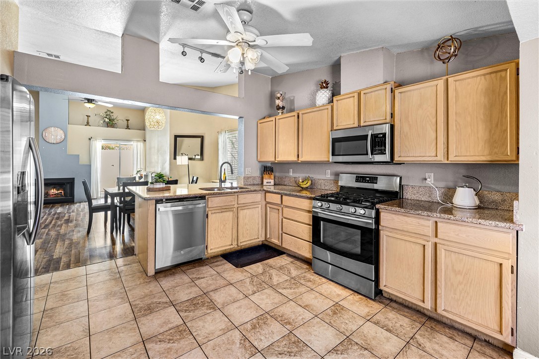 1624 Palmae Way Las Vegas, NV 89128 - Photo 7 of 18 A well-appointed kitchen features stainless steel appliances, granite countertops, and an inviting view into the adjacent dining area.