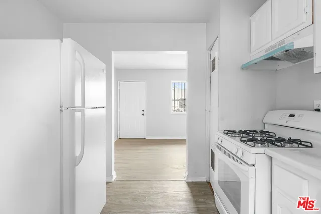 a kitchen with cabinets stainless steel appliances a sink and wooden floor