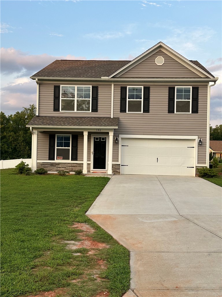 A newly constructed residence features a well-maintained lawn and an attached two-car garage.