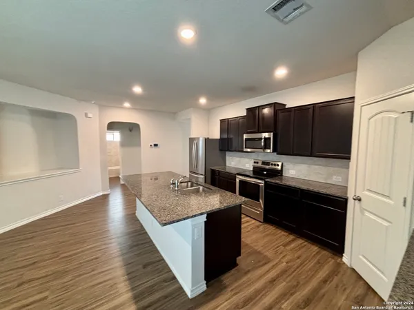 a large kitchen with wooden floors stainless steel appliances and a counter space