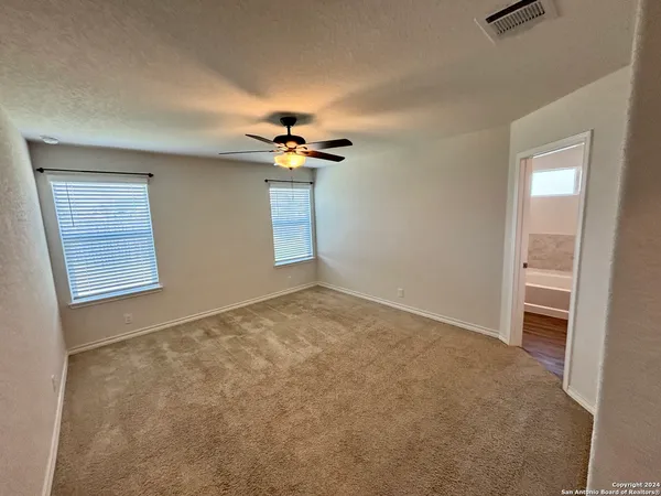 an empty room with windows and chandelier fan