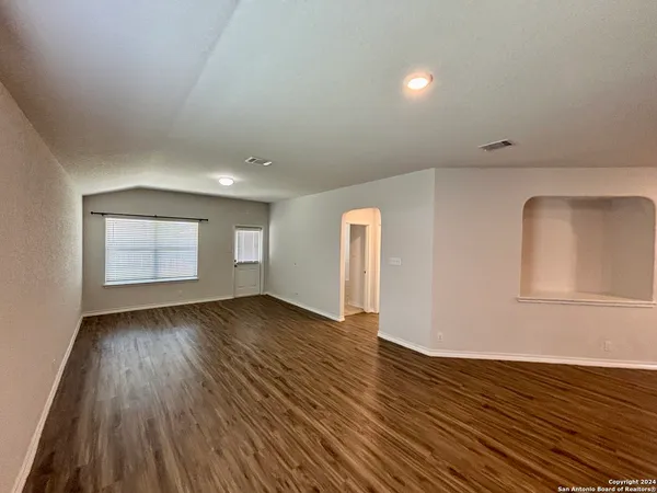 a view of an empty room with wooden floor and a window